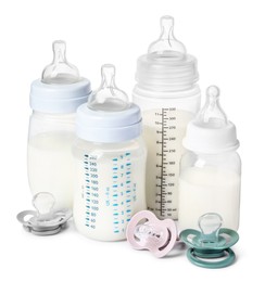 Photo of Many feeding bottles with infant formula and pacifiers on white background