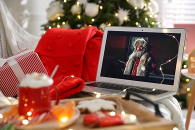 MYKOLAIV, UKRAINE - DECEMBER 25, 2020: Laptop displaying Christmas Chronicles movie at home. Cozy winter holidays atmosphere