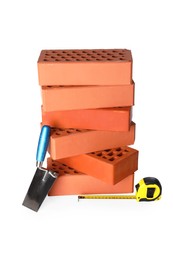 Photo of Many red bricks, trowel and tape measure on white background