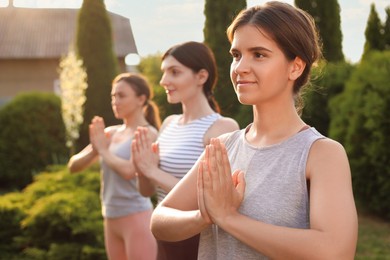 Young women practicing yoga outdoors on sunny day