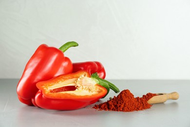 Fresh bell peppers and scoop of paprika powder on white table