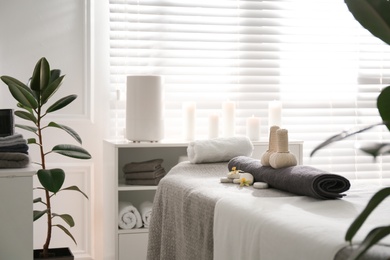Photo of Herbal bags, towel and stones on couch in spa salon