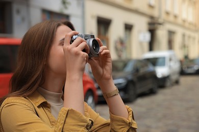 Photo of Young woman with camera taking photo on city street, space for text. Interesting hobby