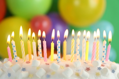 Birthday cake with burning candles against blurred background, closeup