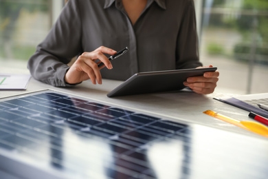 Woman working on  project with solar panels at table in office, closeup