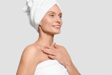 Photo of Woman applying body cream onto her collarbone against white background, space for text