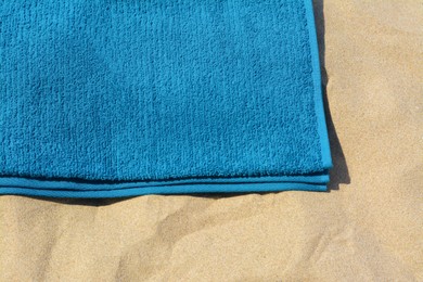 Soft blue beach towel on sand, above view