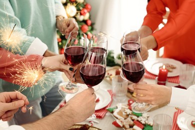 Family with their friends clinking glasses at festive dinner indoors, closeup. Christmas Eve celebration