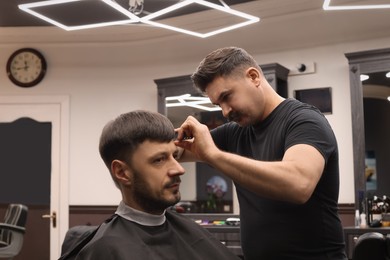 Professional hairdresser making stylish haircut in barbershop