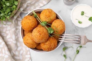 Photo of Bowl of delicious fried tofu balls with pea sprouts and sauce on white marble table, flat lay