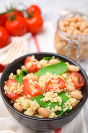 Delicious quinoa salad with tomatoes, beans and spinach leaves served on table