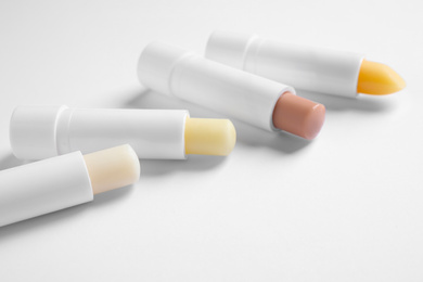 Different open hygienic lipsticks on white background