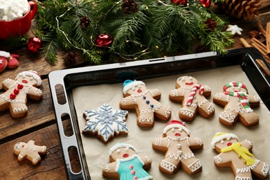 Photo of Making homemade Christmas cookies. Gingerbread people and festive decor on wooden table