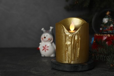 Golden LED candle and Christmas decor on black table. Space for text