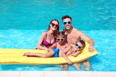 Happy family with inflatable mattress in swimming pool
