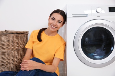 Young woman near washing machine at home. Laundry day