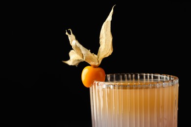 Tasty cocktail decorated with physalis fruit on black background, closeup
