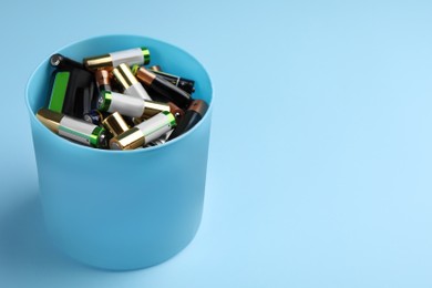 Image of Used batteries in bucket on light blue background, space for text