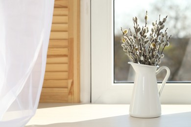 Beautiful pussy willow branches in vase on window sill indoors, space for text