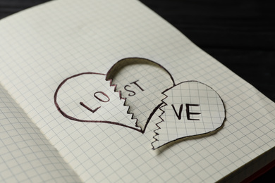 Broken heart with words LOVE and LOST in notebook on table, closeup. Relationship problems concept