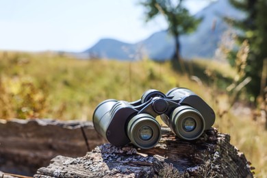 Modern binoculars on wooden surface outdoors. Camping equipment