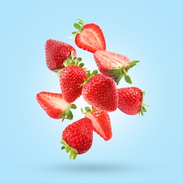Image of Delicious sweet strawberries falling on light blue background