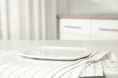 Empty plate and napkin on white table indoors