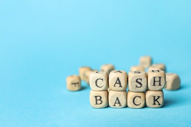 Word Cashback made with cubes on light blue background, closeup. Space for text