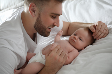 Father with his newborn son on bed