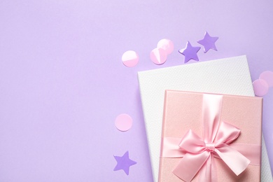 Beautiful gift boxes and confetti on violet background, flat lay. Space for text