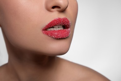 Young woman with lips covered in sugar on light background, closeup. Space for text