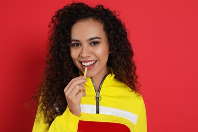 African American woman eating French fries on red background