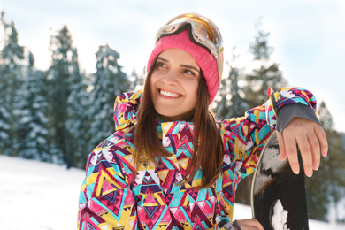 Young woman with snowboard on snowy slope. Winter vacation