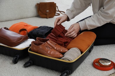 Woman packing suitcase for trip at home, closeup