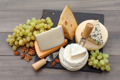Different types of delicious cheeses and snacks on wooden table, above view