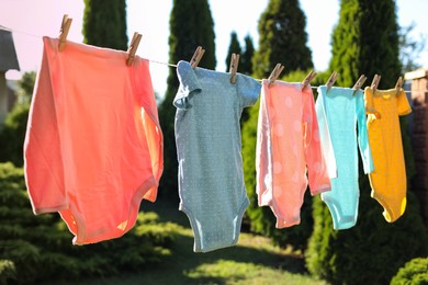 Baby bodysuits drying on washing line outdoors