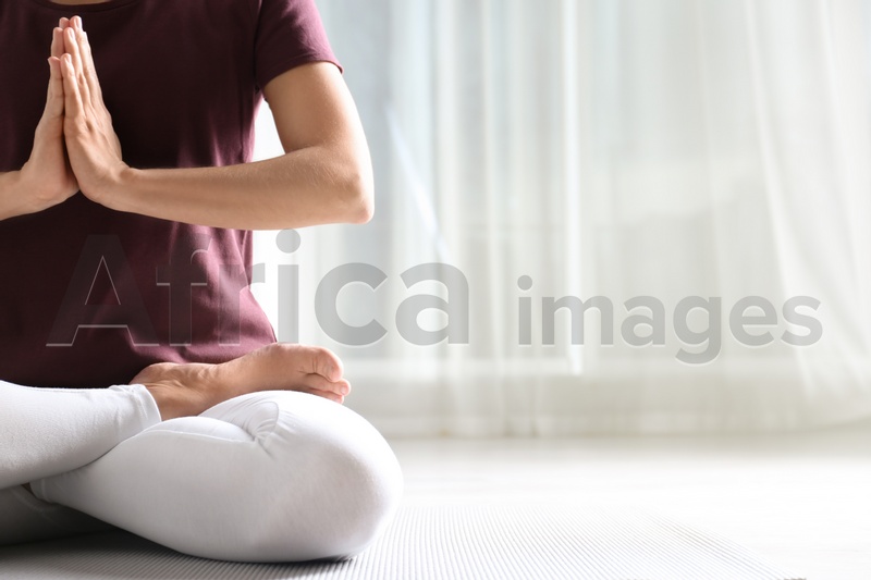 Woman practicing yoga on floor indoors, closeup. Space for text