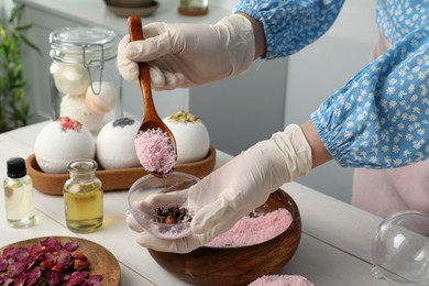 Woman in gloves making bath bomb at white table indoors, closeup