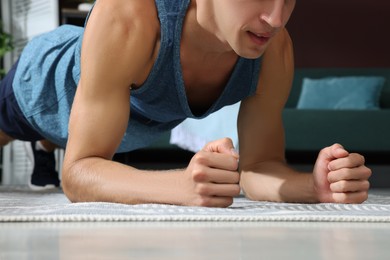 Man doing plank exercise on floor at home, closeup