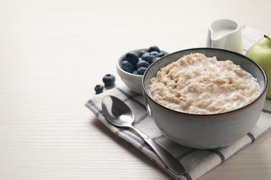 Tasty oatmeal porridge served on light wooden table, space for text