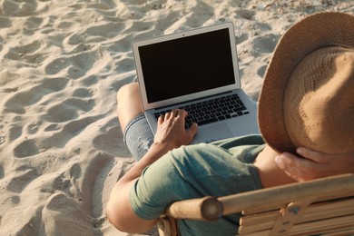 Man working with laptop in deck chair on beach, closeup