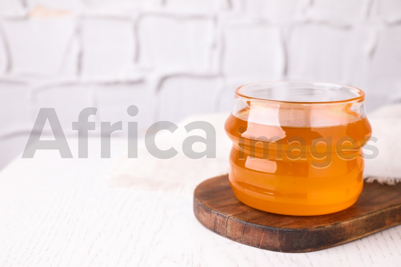 Photo of Tasty aromatic honey on white wooden table. Space for text