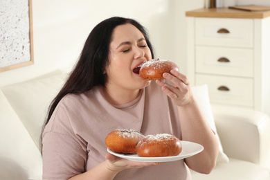 Lazy overweight woman eating buns at home