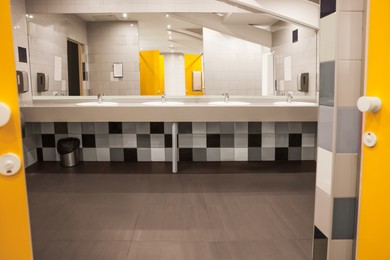 Public toilet interior with sinks, mirror and colorful tiles