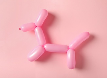 Dog figure made of modelling balloon on pink background, top view