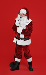 Santa Claus with headphones and microphone on red background. Christmas music