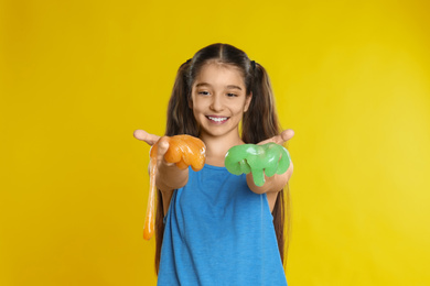 Preteen girl with slime on yellow background