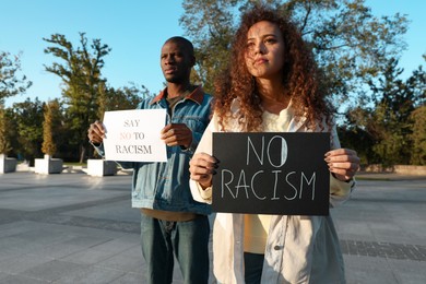 African American woman and man holding signs with phrase Say No To Racism outdoors