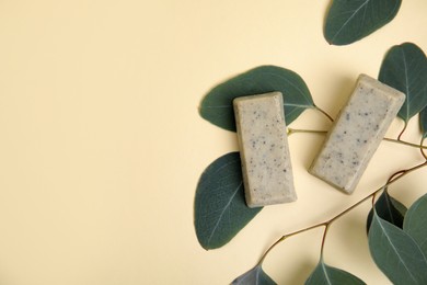 Flat lay of soap bars and green leaves on beige background, space for text. Eco friendly personal care product
