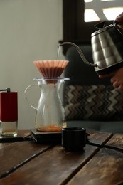 Photo of Barista preparing coffee at wooden table in cafe, closeup